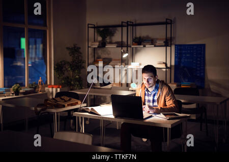 Fiducioso studente studiare in biblioteca a notte Foto Stock