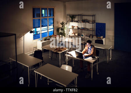 Angolo di alta vista di apprendimento dello studente attraverso il computer portatile nella libreria Foto Stock