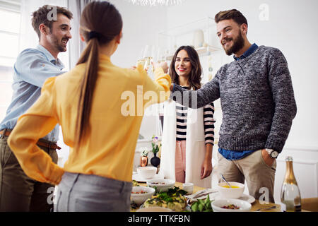 Happy amici sollevamento brindisi celebrativo in parte il pranzo Foto Stock