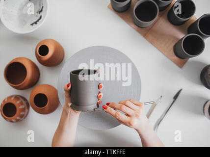 Tagliate le mani femminili di potter far ceramica a tavola in officina Foto Stock