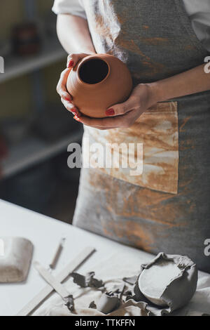 Sezione mediana del potter femmina holding pot permanente, mentre dalla tabella in officina Foto Stock