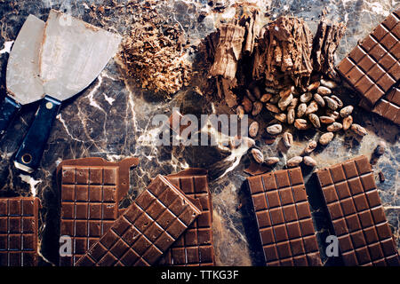 Vista aerea di barrette di cioccolato con noci e coltello da cucina sul tavolo Foto Stock