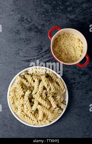 Vista aerea di pasta servita da formaggio Cheddar grattugiato in ciotole sul tavolo Foto Stock