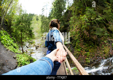 Le persone camminare sul ponte di legno attraverso il fiume di montagna. Follow me concetto Foto Stock