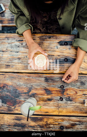 Angolo di elevata sezione mediana della donna con drink al cafè sul marciapiede Foto Stock