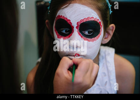 Immagine ritagliata della donna di applicare il make-up sulla mia figlia di fronte a casa Foto Stock