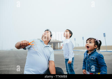 Padre Holding Slingshot con la figlia e il figlio figlia in soggezione Foto Stock