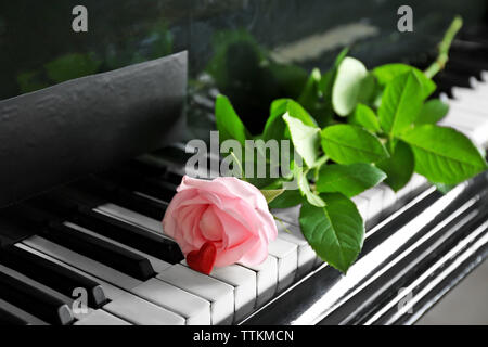 Bella rosa rosa e un po' di cuore rosso su tasti di pianoforte, close up Foto Stock