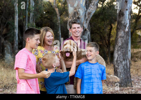 Labradoodle felice tra le braccia del padre mentre i figli e la moglie guarda Foto Stock