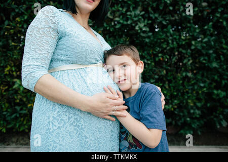 Presto per essere grande fratello si appoggia sulla testa della madre di bump baby Foto Stock