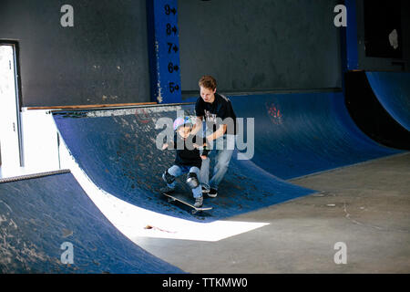 Istruttore di skateboard aiuta a studente skate verso il basso una rampa Foto Stock