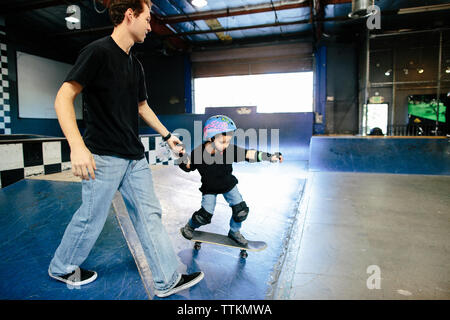 Skateboard istruttore tiene le mani al fianco di studente su skateboard Foto Stock