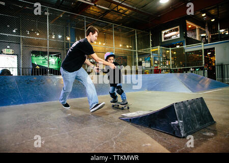 Lo skateboard istruttore tiene per mano e funziona con gli studenti per un salto Foto Stock