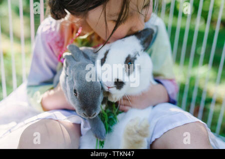 Angolo di Alta Vista della ragazza che gioca con i conigli in cantiere Foto Stock