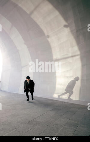 Giovane uomo guardando ombra mentre è in esecuzione nel tunnel Foto Stock