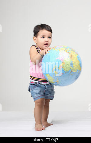 Baby girl playing with a globe Foto Stock