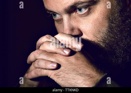 Close-up di grave uomo contro lo sfondo nero Foto Stock