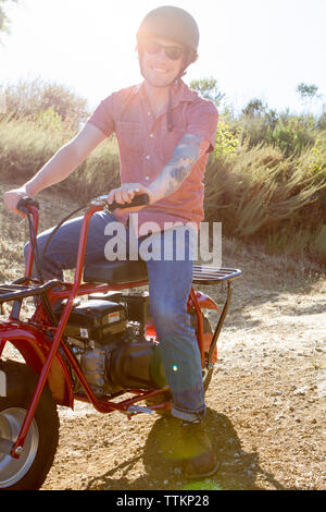 Ritratto di uomo sorridente con il motociclo sul campo contro sky Foto Stock