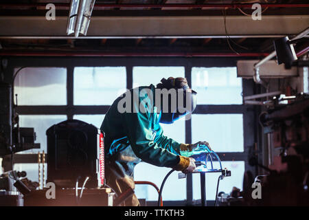 Lavoratore utilizzando la torcia di saldatura in officina Foto Stock