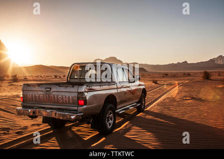 Un turista Mitsubishi jeep al tramonto nel deserto giordano a Wadi Rum o a valle della luna. Foto Stock