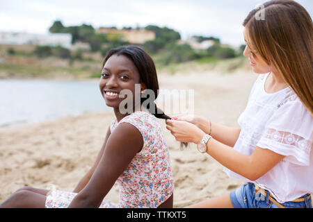 Vista laterale della calza donna amico di capelli in spiaggia Foto Stock