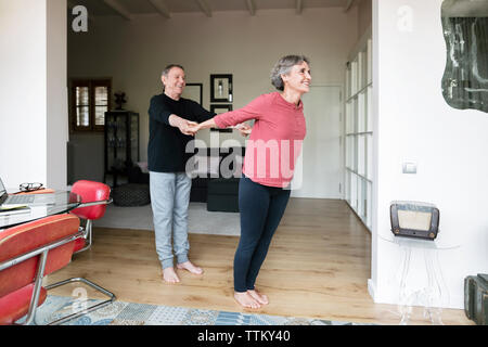 Uomo senior di aiutare la donna a fare yoga Foto Stock