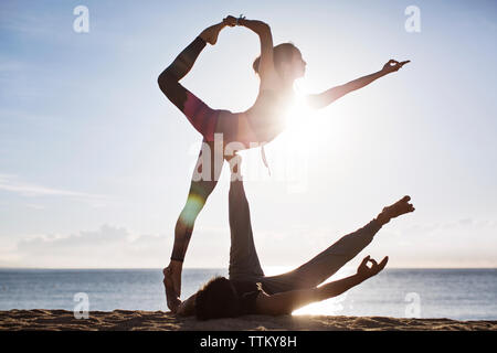 Giovane fare yoga sulla spiaggia contro sky durante l'estate Foto Stock