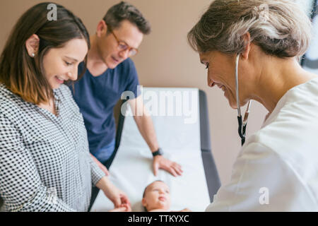 Close-up di medico esaminando baby boy con i genitori in ospedale Foto Stock