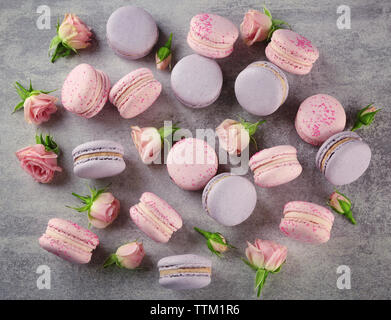 Gustosi amaretti con bellissime rose sul tavolo Foto Stock