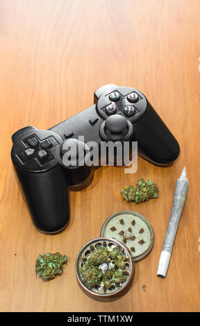 Video giochi e la cannabis. Video controller di gioco, grande e comune di Mola con boccioli di marijuana sul tavolo di legno con spazio copia top. Foto Stock