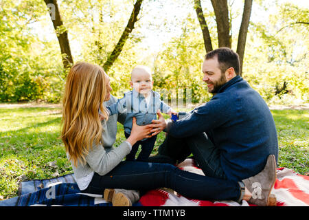 Una famiglia con un bambino si siede insieme su una coperta Foto Stock