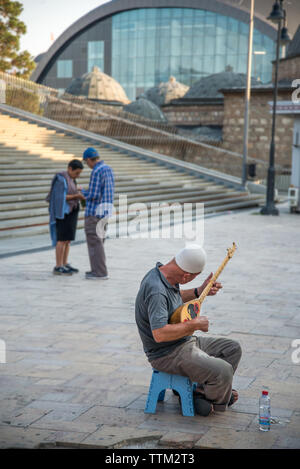 Uomo anziano riproduce la musica su un tradizionale. Cifteli albanese, una chitarra,nel Vecchio Bazar area di Skopje. Foto Stock