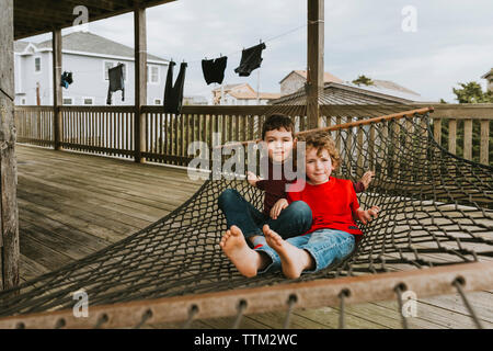 Ritratto di simpatici fratelli relax su amaca in balcone presso una località turistica Foto Stock