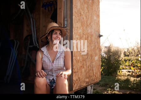 Felice agricoltore femmina seduto in cabina su campo Foto Stock