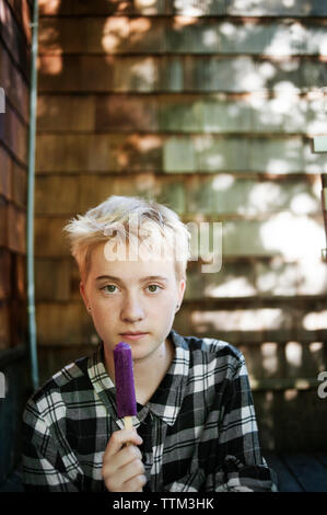 Ritratto di ragazza adolescente holding ice candy in cortile Foto Stock