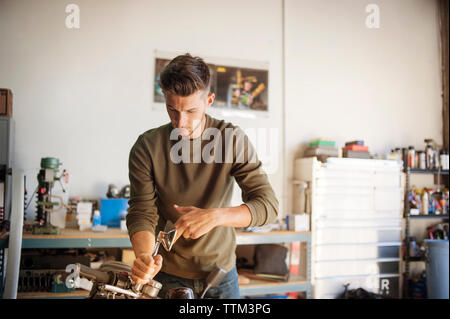 Uomo al lavoro su motociclo in garage Foto Stock