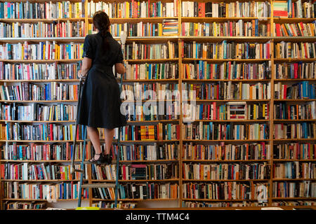 Il cliente sui passi guardando libri all'interno di St Georges usati a bookshop in Prenzlauer Berg di Berlino, Germania Foto Stock