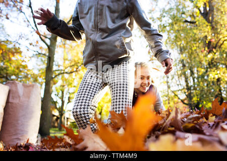 Amici a giocare con le foglie di autunno su strada Foto Stock