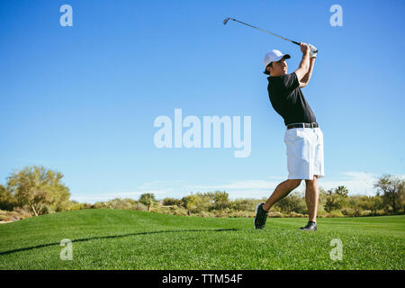 Il Golfer giocando sul campo contro sky Foto Stock