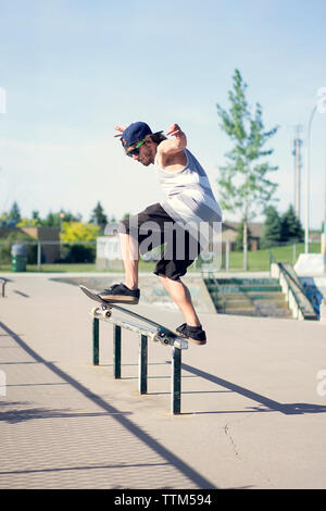 Giovane uomo lo skateboard su parapetto Foto Stock