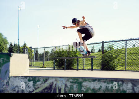 Giovane uomo lo skateboard su parapetto Foto Stock