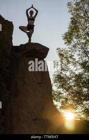 Stagliano arrampicatori sulla sommità della parete di roccia nella posizione del loto Foto Stock