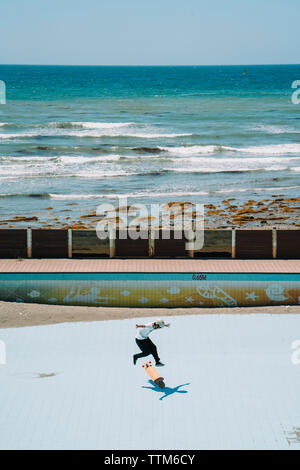 Elevato angolo di visione dell'uomo lo skateboard al parco dal mare Foto Stock