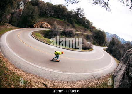 Elevato angolo di visione dell'uomo lo skateboard su tornante strada contro sky Foto Stock