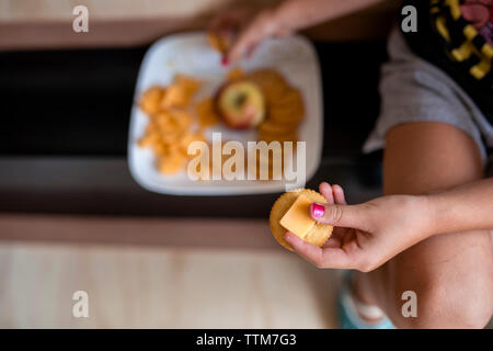 Immagine ritagliata della ragazza il contenimento di cibo mentre è seduto alla porta Foto Stock