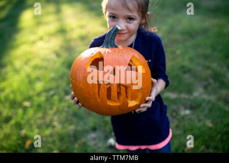 Ritratto di ragazza con jack o lantern mentre si sta in piedi sul campo in cantiere Foto Stock