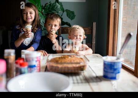 Tre giovani fratelli godendo di dolci prelibatezze in ambienti interni Foto Stock