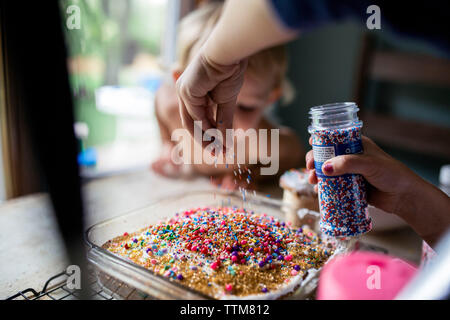 Un giovane bambino decorazione torta fresca con un sacco di spruzza Foto Stock