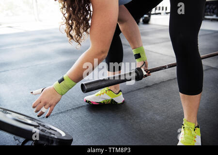 Donna modifica piastre di peso mentre ti alleni con barbell in palestra crossfit Foto Stock