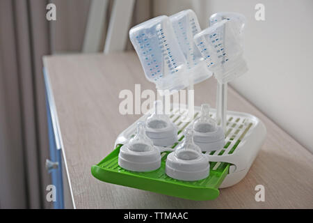 Baby bottiglie in plastica rack di asciugatura su una superficie di legno Foto Stock